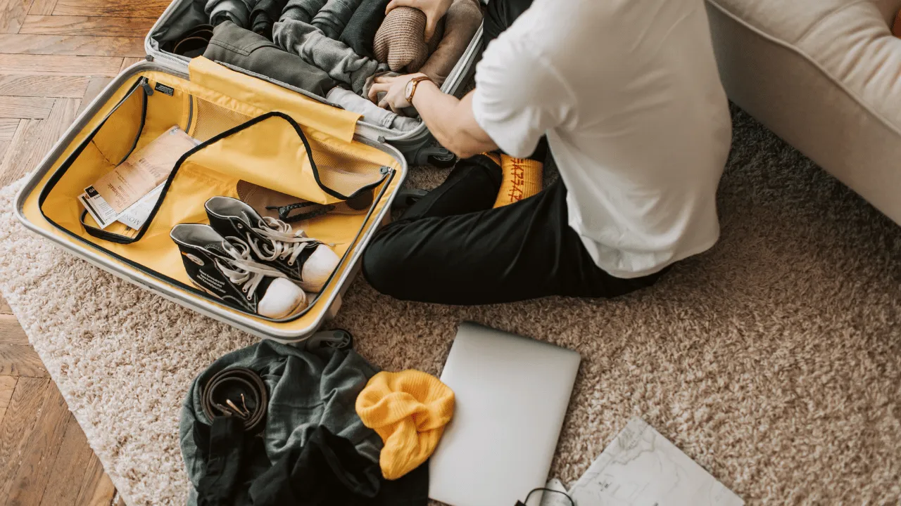 Ein Reisender packt vor seiner Reise nach Valencia einen Koffer mit Kleidung und Turnschuhen.